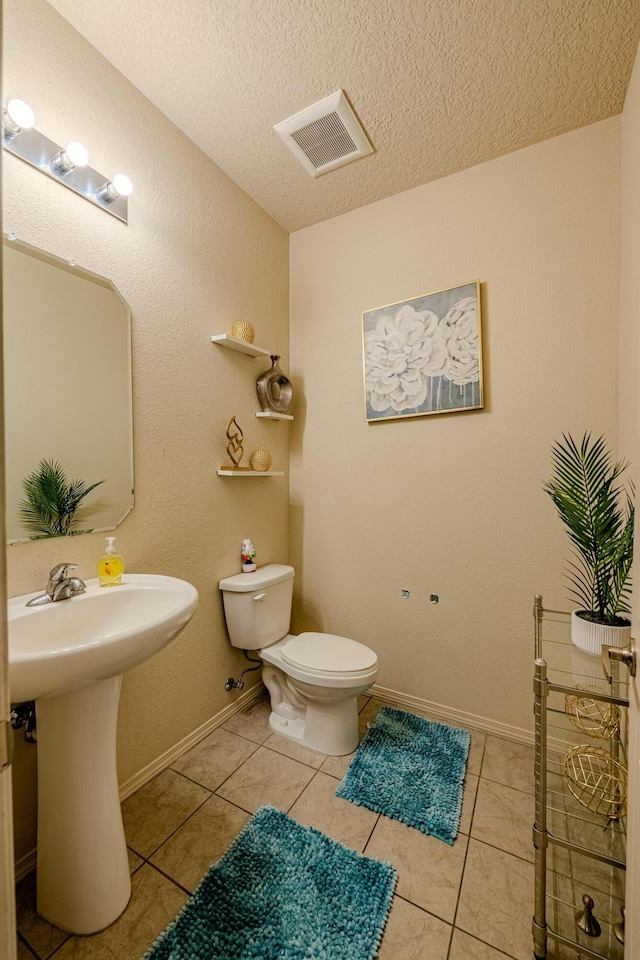 bathroom with toilet, tile patterned flooring, and a textured ceiling