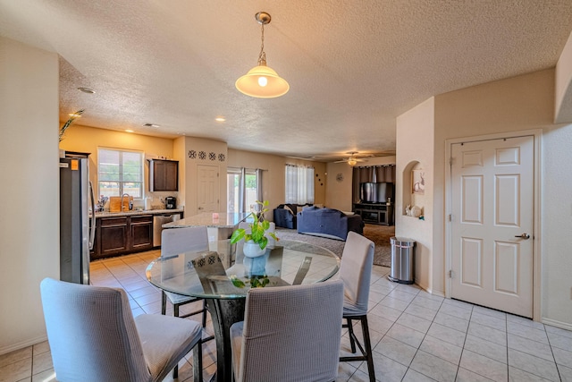 tiled dining area with sink, a textured ceiling, and a wealth of natural light