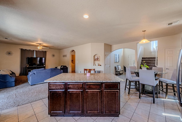 kitchen with pendant lighting, light tile patterned floors, dark brown cabinetry, and a kitchen island