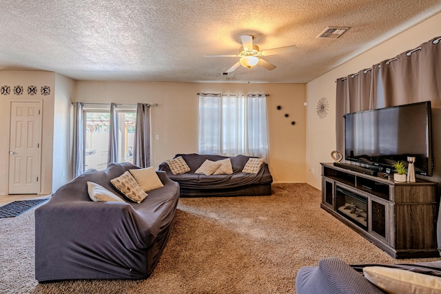 living room featuring ceiling fan, light carpet, and a textured ceiling