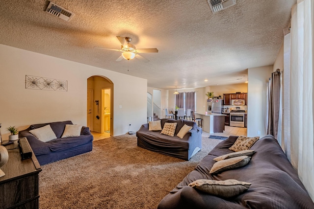 carpeted living room with ceiling fan and a textured ceiling