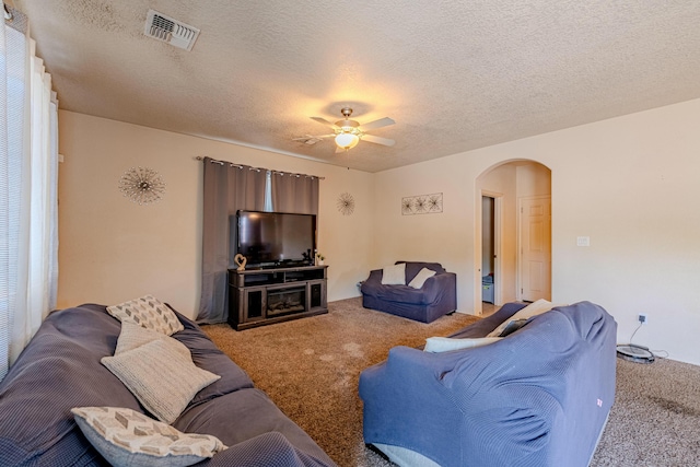 living room with ceiling fan, carpet flooring, and a textured ceiling