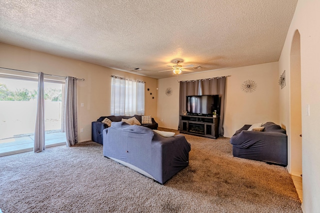 living room with a textured ceiling, carpet floors, and ceiling fan