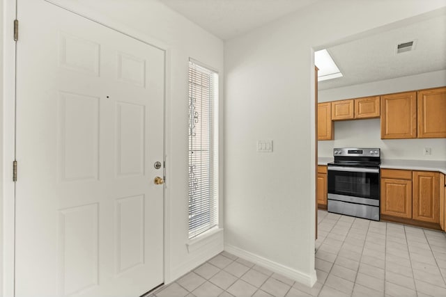 kitchen with light tile patterned floors, stainless steel range with electric cooktop, and a healthy amount of sunlight