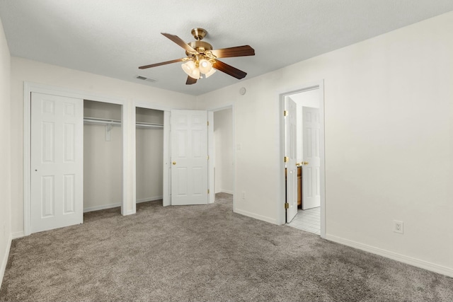 unfurnished bedroom featuring light carpet, ceiling fan, and multiple closets