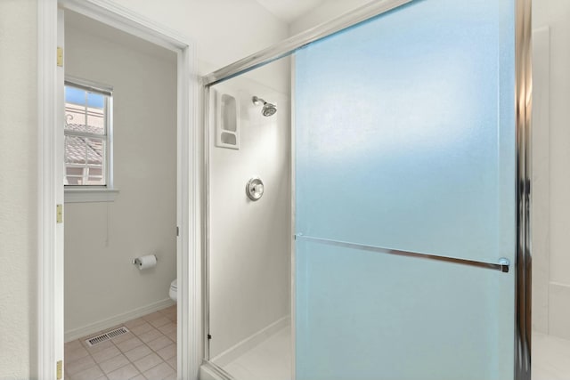 bathroom with a shower with door, tile patterned flooring, and toilet