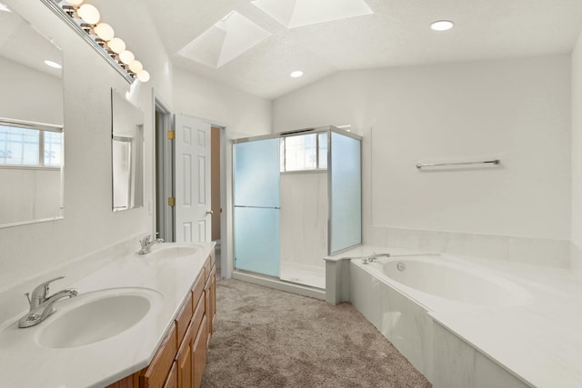 bathroom with vanity, independent shower and bath, and vaulted ceiling with skylight