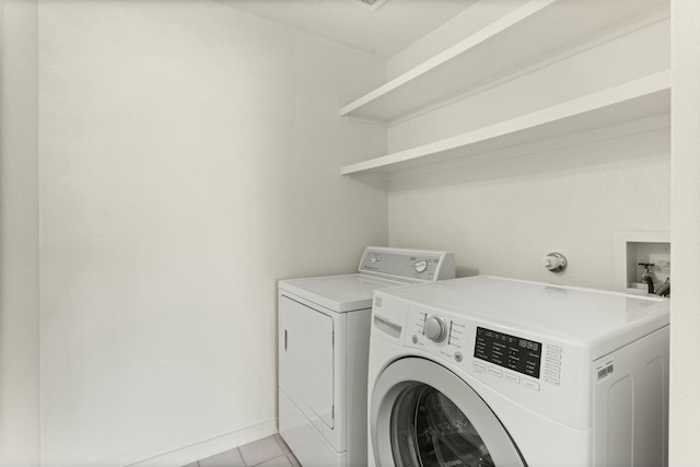 clothes washing area featuring light tile patterned flooring and washing machine and clothes dryer