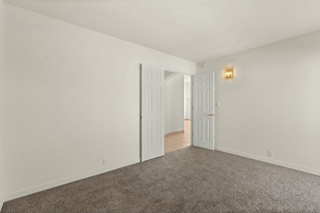 spare room with light colored carpet and a textured ceiling