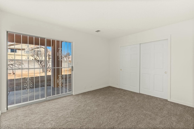 unfurnished bedroom featuring carpet flooring, access to exterior, and a closet