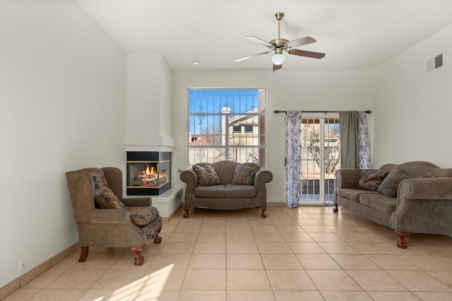 living room with light tile patterned floors, ceiling fan, and a multi sided fireplace