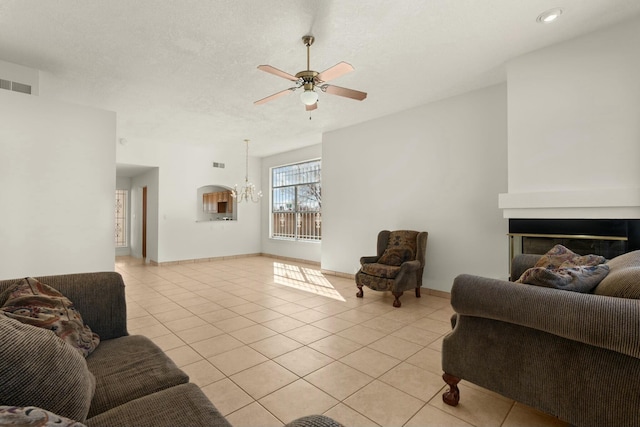 living room with ceiling fan with notable chandelier, light tile patterned floors, and a textured ceiling