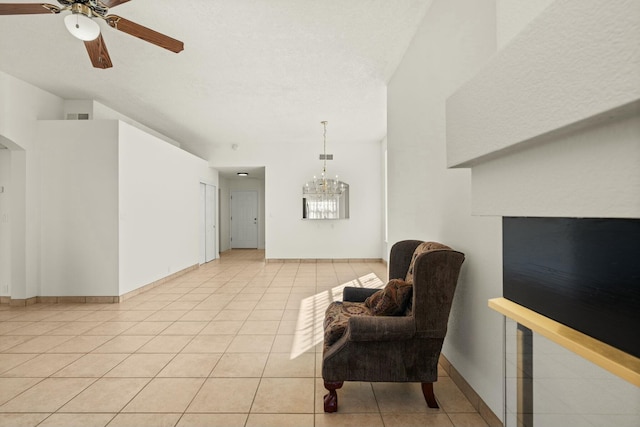 living area featuring light tile patterned floors, ceiling fan with notable chandelier, and a textured ceiling