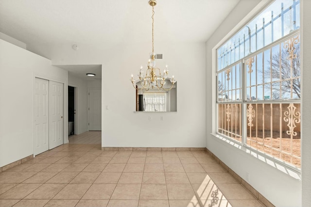 spare room featuring light tile patterned flooring and a notable chandelier