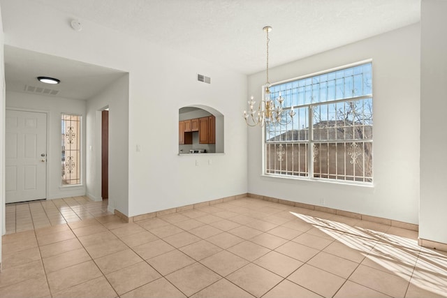 unfurnished dining area with light tile patterned floors, a textured ceiling, and an inviting chandelier