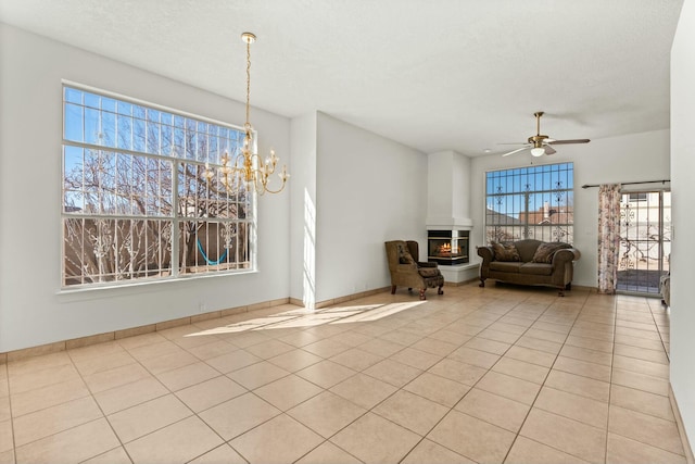 interior space featuring light tile patterned floors, ceiling fan with notable chandelier, a wealth of natural light, and a textured ceiling