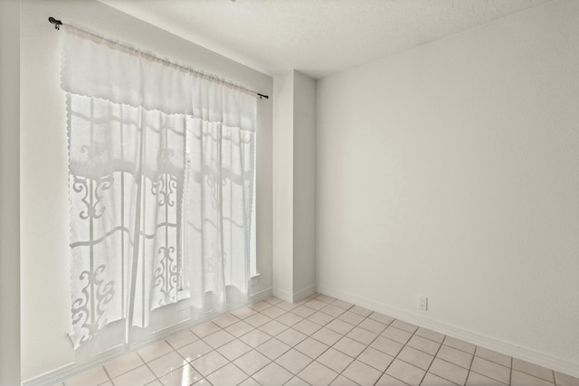 tiled spare room featuring a textured ceiling