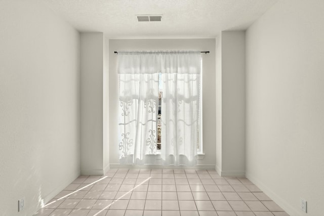 empty room featuring light tile patterned floors and a textured ceiling