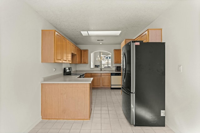 kitchen featuring appliances with stainless steel finishes, light brown cabinetry, sink, kitchen peninsula, and an inviting chandelier