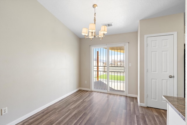 unfurnished dining area featuring an inviting chandelier and dark wood-type flooring