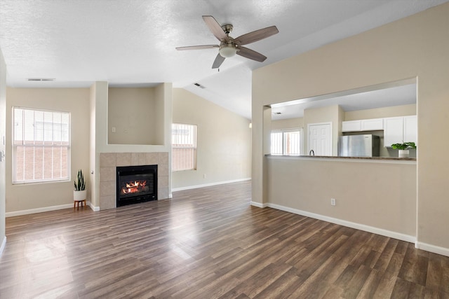 unfurnished living room with a fireplace, a healthy amount of sunlight, dark hardwood / wood-style flooring, and lofted ceiling