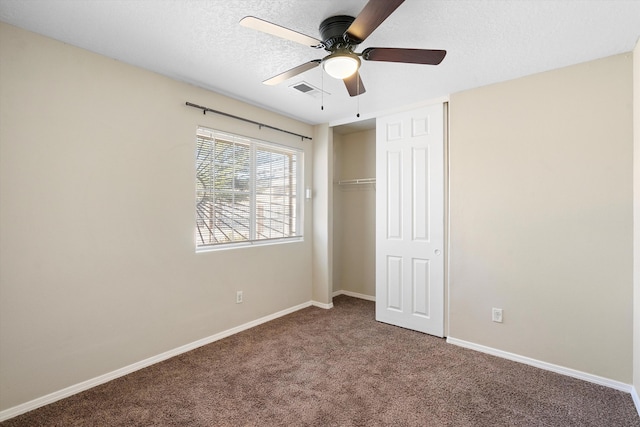 unfurnished bedroom featuring ceiling fan, a closet, carpet floors, and a textured ceiling