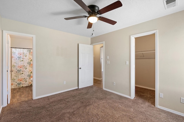 unfurnished bedroom with a walk in closet, carpet flooring, a closet, and a textured ceiling