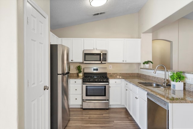 kitchen with sink, white cabinetry, vaulted ceiling, stainless steel appliances, and light stone countertops