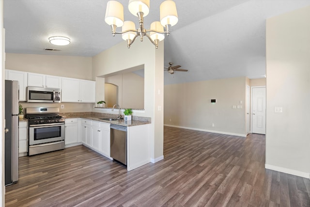 kitchen featuring lofted ceiling, sink, appliances with stainless steel finishes, white cabinetry, and hanging light fixtures