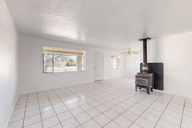 living room with light tile patterned flooring, a textured ceiling, and a wood stove