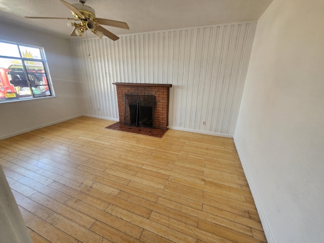 unfurnished living room featuring ceiling fan, a fireplace, and light hardwood / wood-style floors