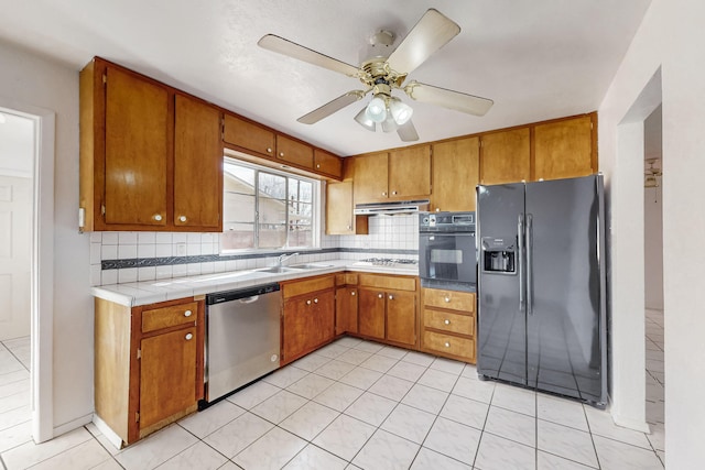 kitchen featuring sink, decorative backsplash, black appliances, and light tile patterned flooring