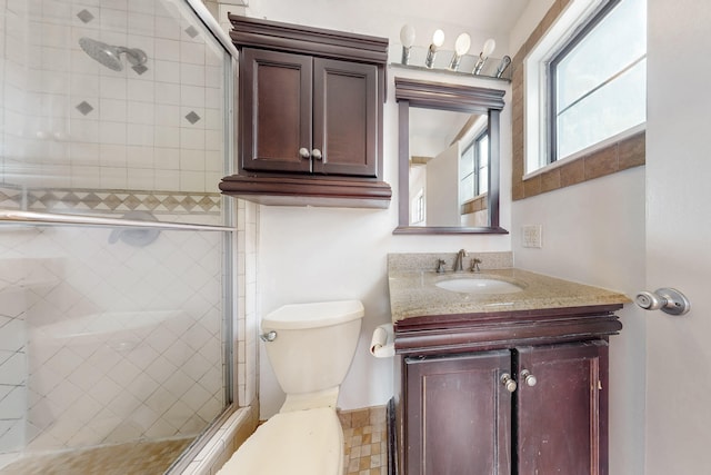 bathroom featuring vanity, a shower with door, and toilet