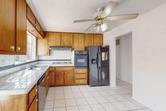 kitchen featuring sink, ceiling fan, backsplash, black appliances, and tile countertops