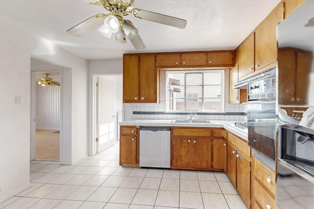 kitchen featuring sink, black oven, dishwasher, light tile patterned flooring, and decorative backsplash