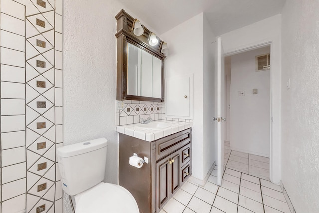 bathroom featuring tasteful backsplash, vanity, tile patterned flooring, and toilet