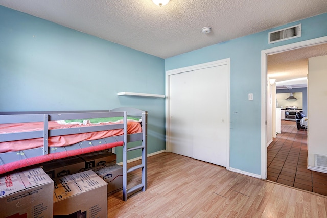 bedroom featuring a textured ceiling, light wood-type flooring, and a closet