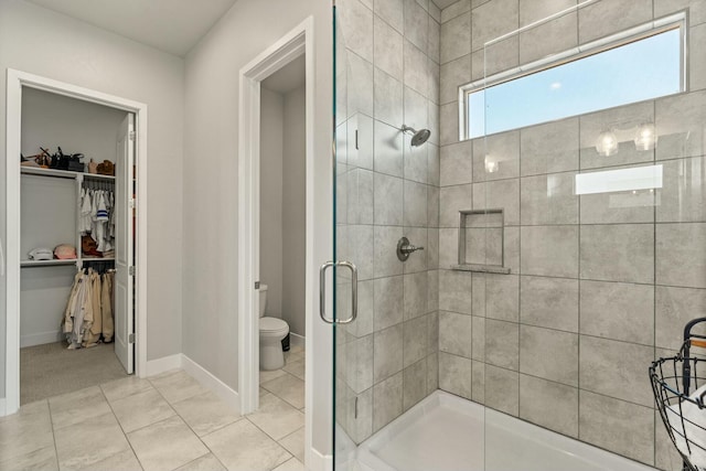 bathroom featuring toilet, a shower with shower door, and tile patterned flooring