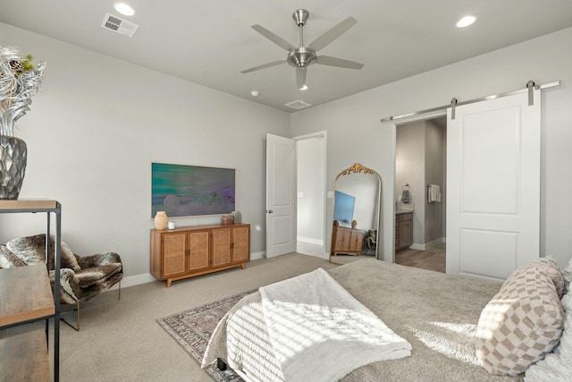 bedroom with connected bathroom, carpet floors, a barn door, and ceiling fan