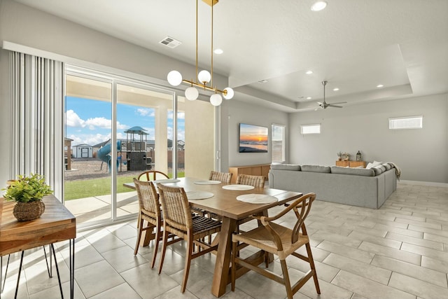 dining area with ceiling fan and a tray ceiling