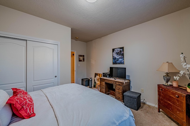 carpeted bedroom with a textured ceiling and a closet