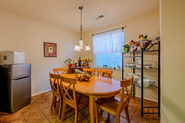 tiled dining room with a textured ceiling and a chandelier