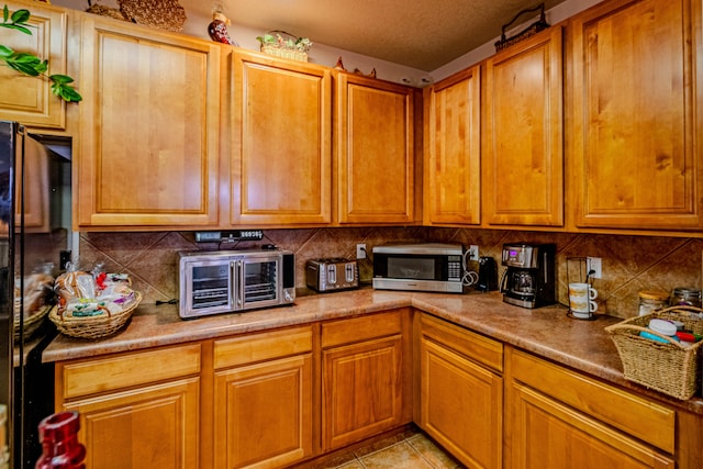 kitchen featuring black fridge, light tile patterned floors, and decorative backsplash