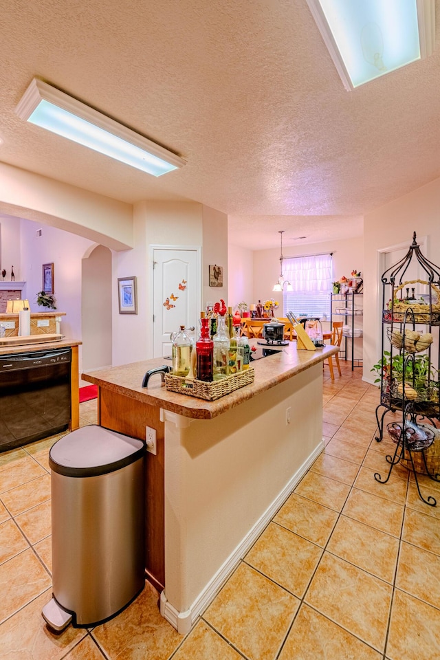 kitchen featuring dishwasher, light tile patterned flooring, a textured ceiling, and a kitchen island