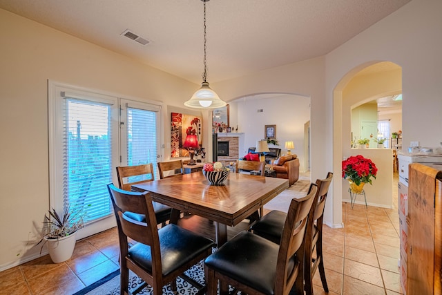 tiled dining room with plenty of natural light and a fireplace