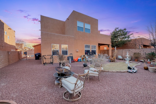 back house at dusk with an outdoor fire pit and a patio area