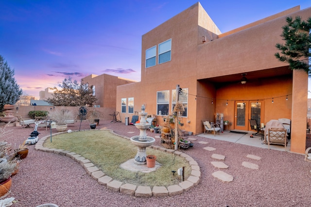 back house at dusk featuring a patio and ceiling fan