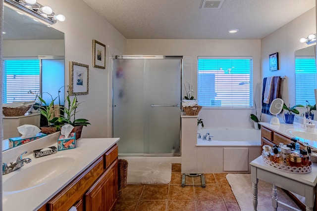 bathroom with tile patterned flooring, vanity, plus walk in shower, and a textured ceiling