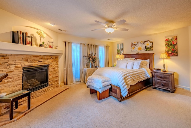 carpeted bedroom featuring ceiling fan, a fireplace, and a textured ceiling