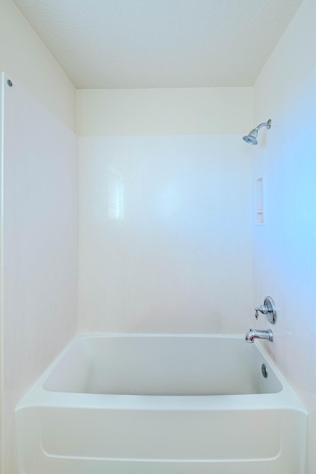 bathroom with shower / washtub combination and a textured ceiling